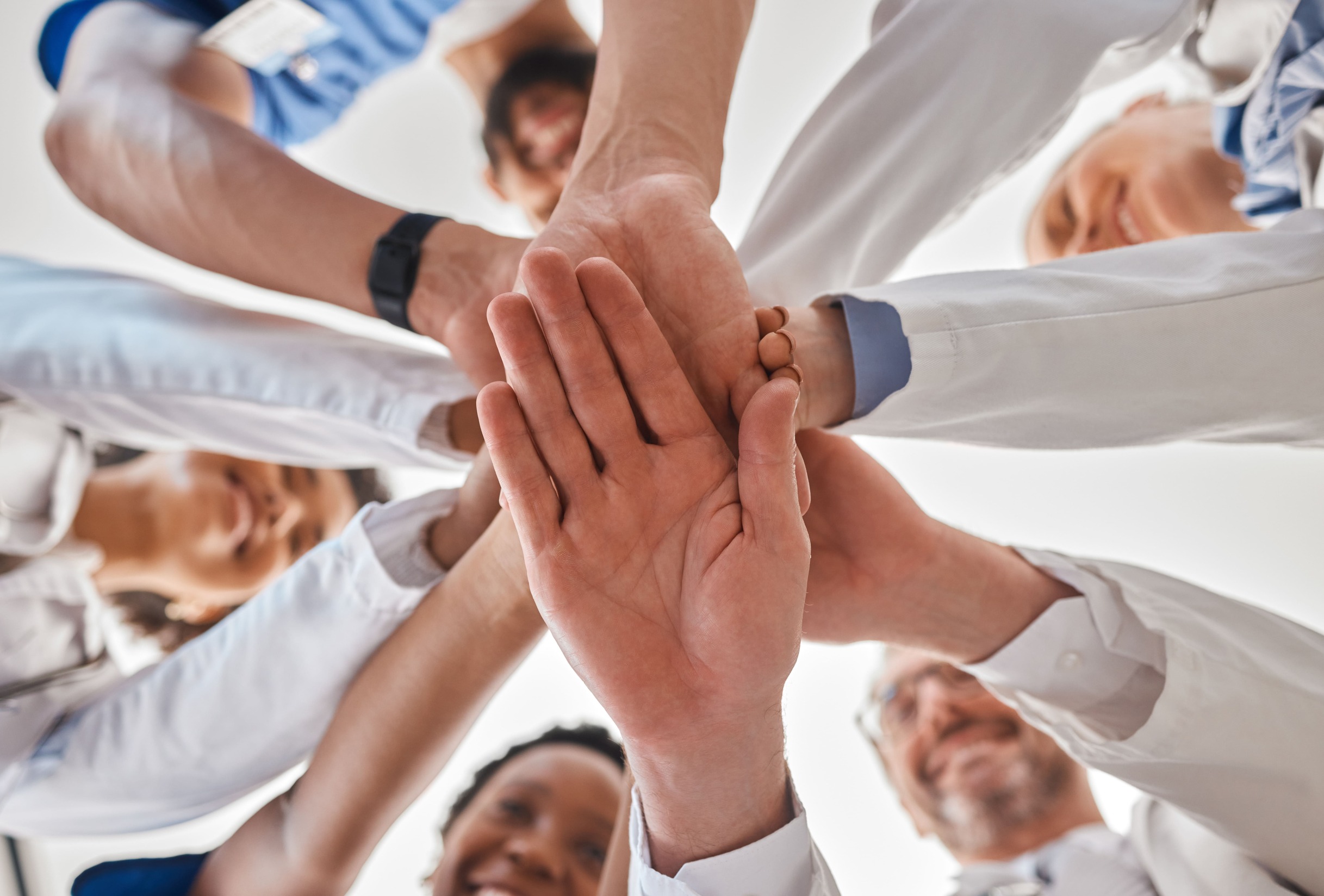 Diverse group of healthcare professionals joining hands in teamwork and unity.